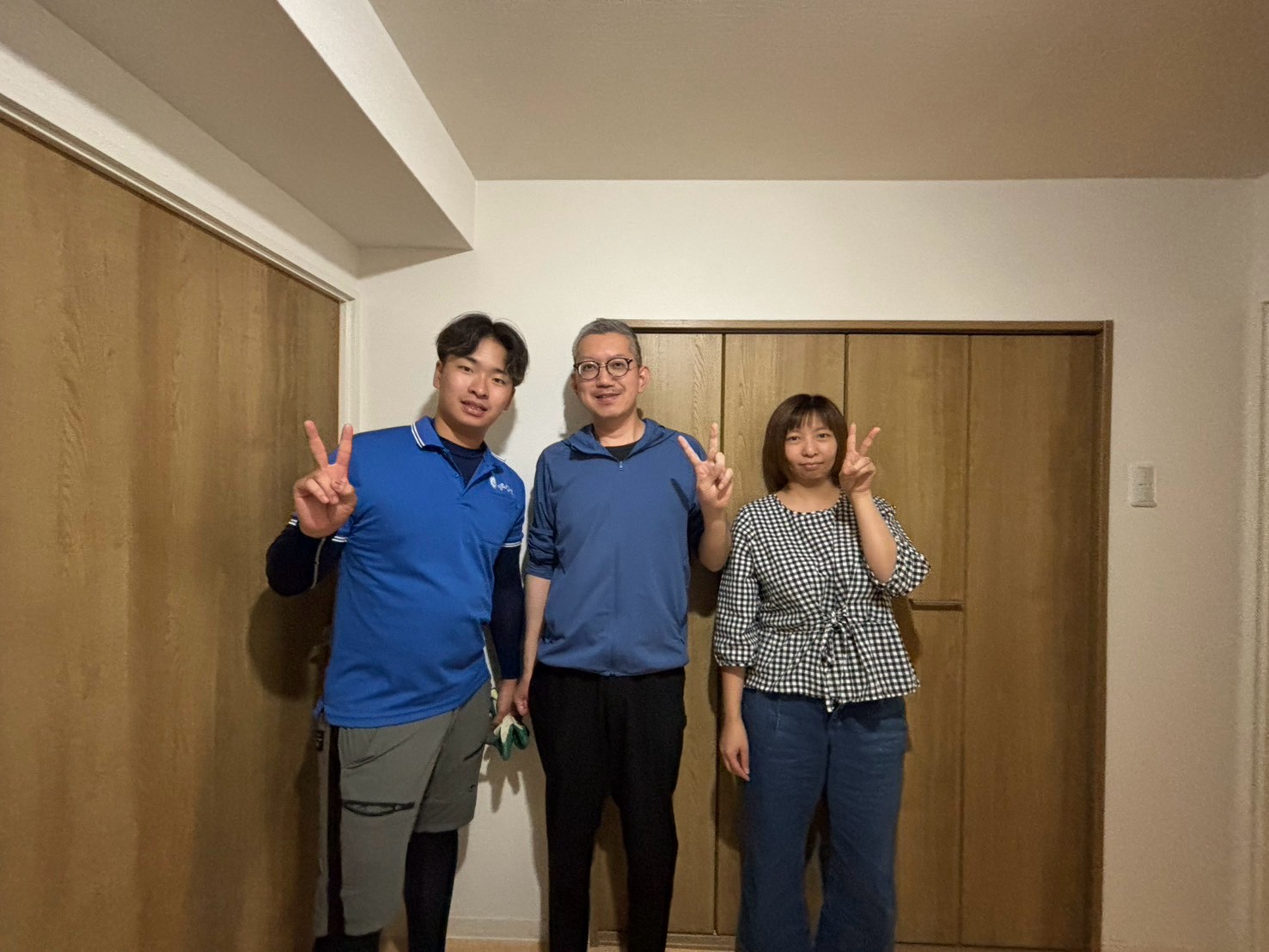 富田林市のマンション前で大型食器棚の回収完了後にお客様と笑顔で並ぶイーブイの作業スタッフ
