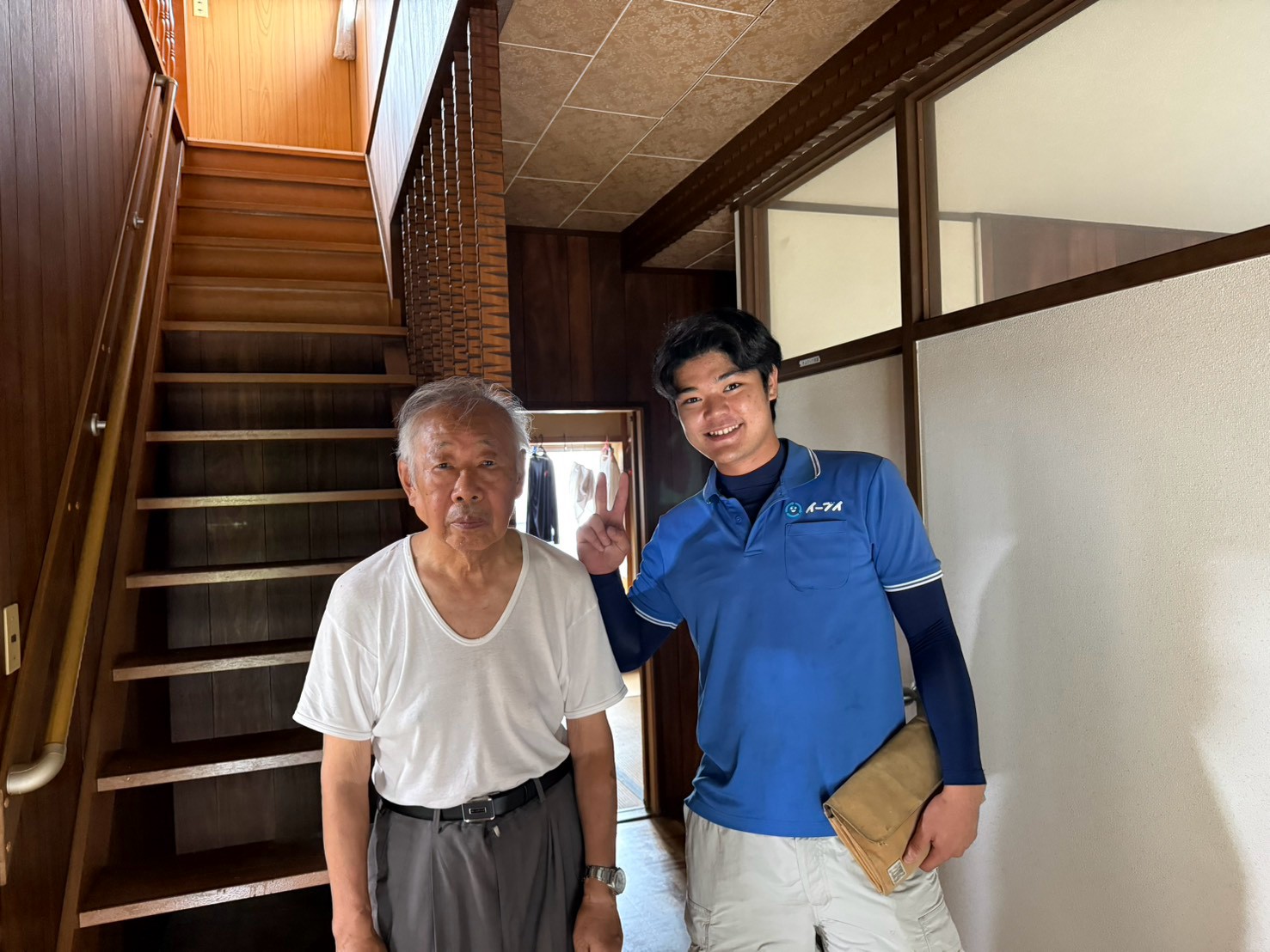 枚方市の戸建て住宅前で飾り棚や額縁の単品回収完了後にお客様と笑顔で並ぶイーブイの作業スタッフ