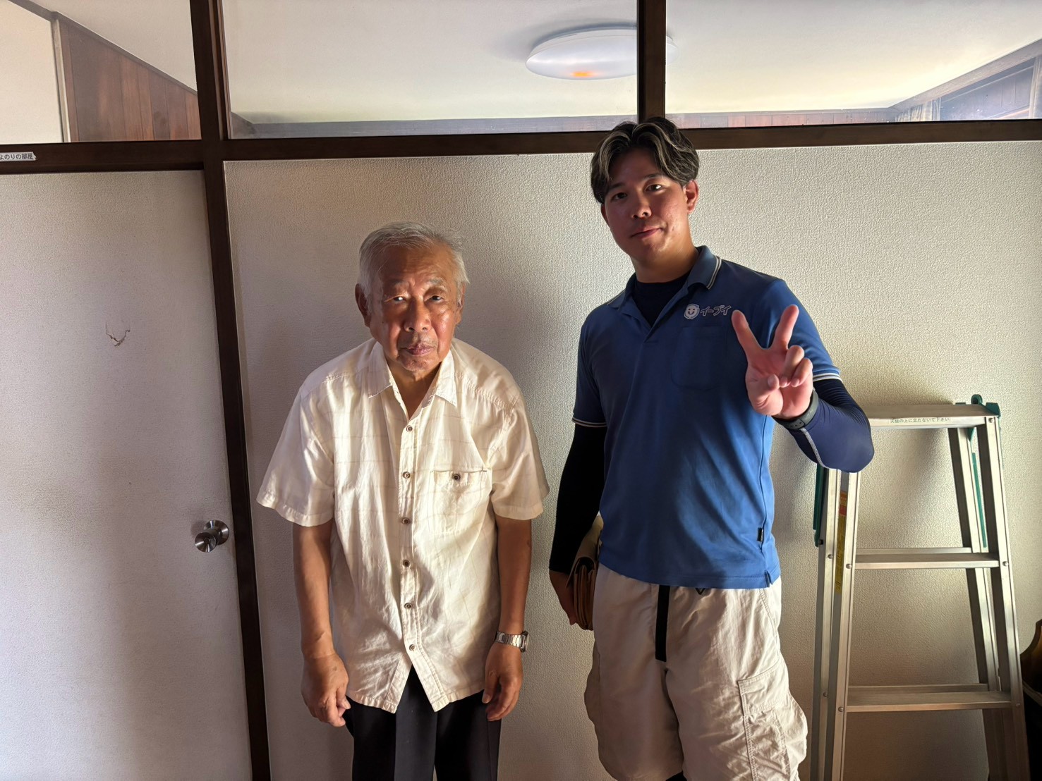 枚方市の一軒家前で遺品整理の家財搬出完了後にお客様と笑顔で並ぶイーブイの作業スタッフ