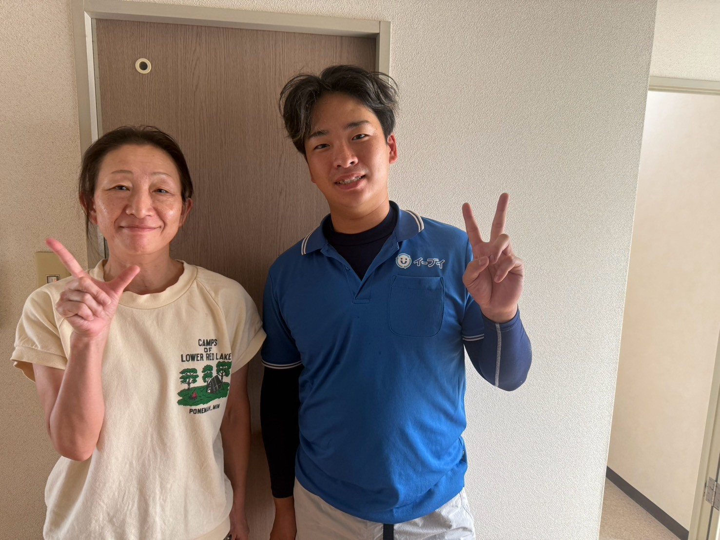 大阪市東淀川区のマンション前で階段からの不用品回収完了後にお客様と笑顔で並ぶイーブイの作業スタッフ