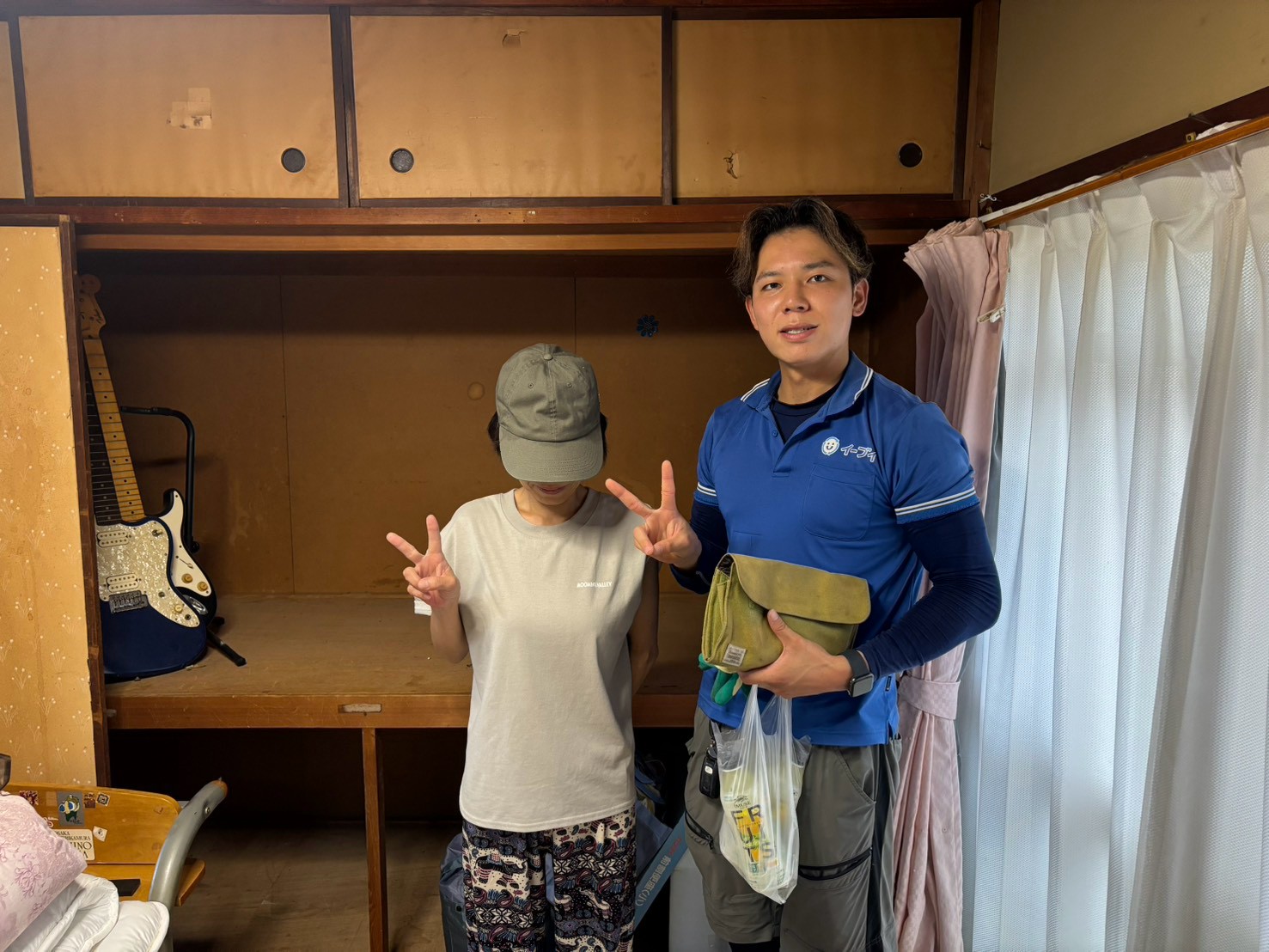 寝屋川市の市営住宅前で家具家電の不用品回収完了後にお客様と笑顔で並ぶイーブイの作業スタッフ